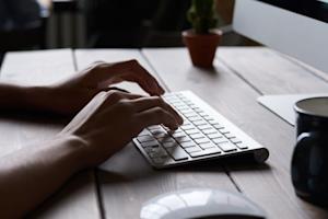 A person typing on a desktop computer keyboard.