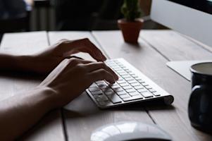 A person typing on a desktop computer keyboard.