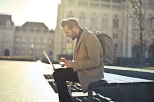 A man sitting outside and working remotely on a laptop.