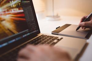 A person using a Wacom tablet next to a laptop
