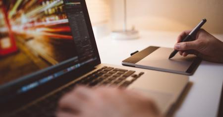 A person using a Wacom tablet next to a laptop