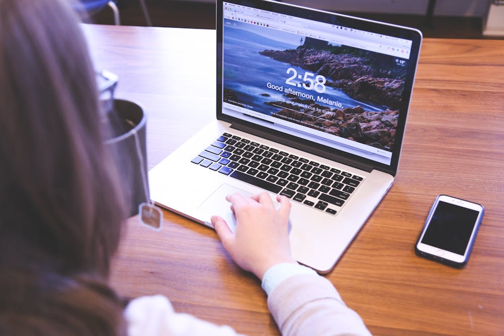 A person typing on a laptop on a desk.