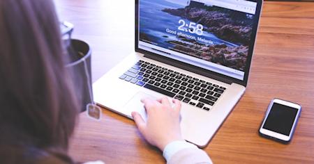 A person typing on a laptop on a desk.