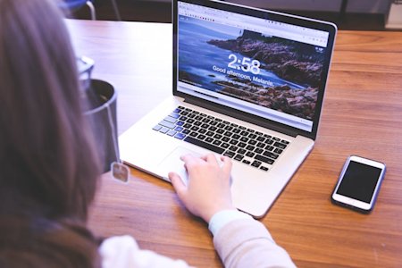 A person typing on a laptop on a desk.