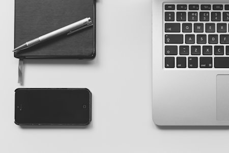 iPhone and MacBook on a desk, representing remote control and access.