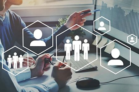 Two people point at a computer screen, superimposed by icons of generic humans