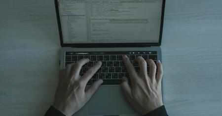 A person's hands on a laptop keyboard.