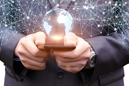 Business professional holding a mobile device with a digital globe and connected network overlay, representing Enterprise Mobility Management (EMM).