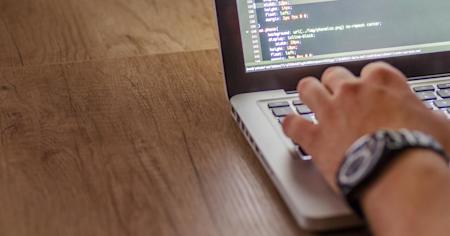 Close up of a hand typing on a laptop keyboard.