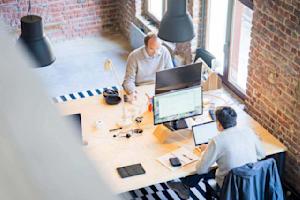 Two workers at their workstations using their computers in an office.