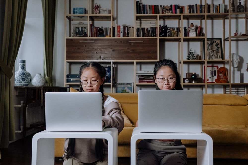 Two kids using laptops in their home.