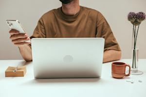 A man using his smartphone and laptop.