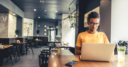 Man using a laptop in a cafe, possibly working remotely with Splashtop