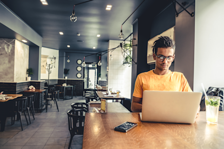 Man using a laptop in a cafe, possibly working remotely with Splashtop