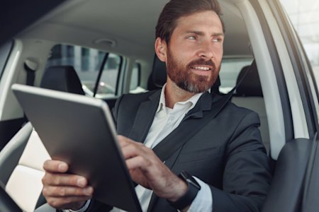 IT Specialist sitting in a car holding a tablet using Splashtop the best Remote Work Software for on the road