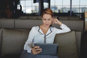 A happy woman using Splashtop on her iPad to remotely access her Mac computer.