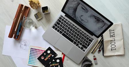 A laptop with graphic design software opened on a desk.