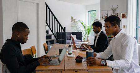 Three people working on their laptops on a shared tabled.