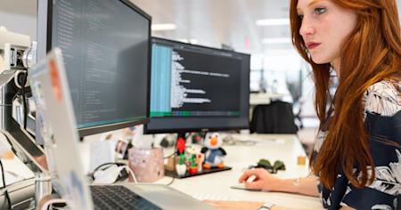A woman working on her computer at her workstation in an office.
