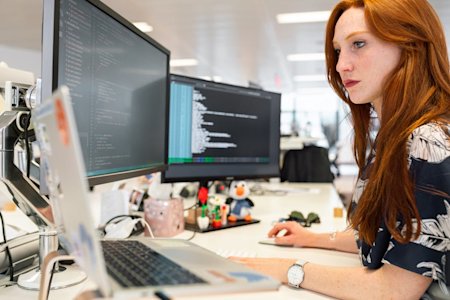 A woman working on her computer at her workstation in an office.
