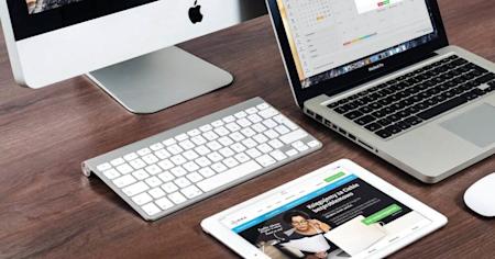 A computer, tablet, and laptop on a desk with multiple apps open.