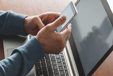 Hands holding a computer in front of a laptop computer
