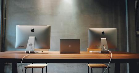 Desktop computers and a laptop sitting on a desk.