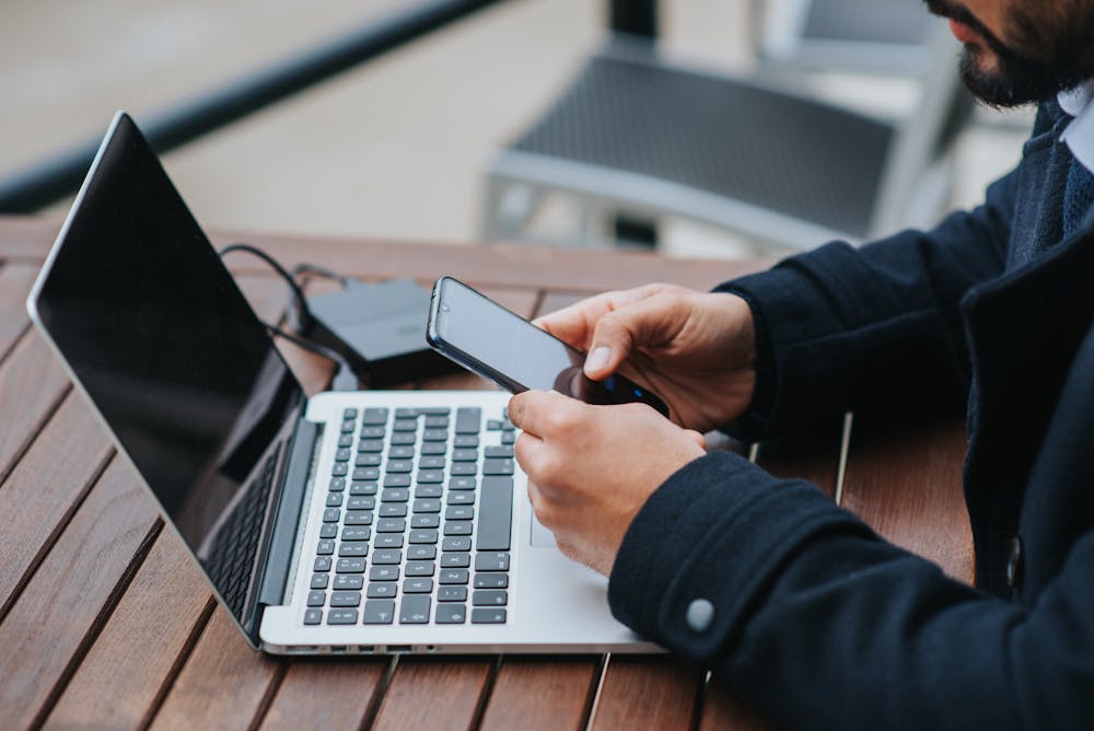 A person using a smartphone and laptop to work.