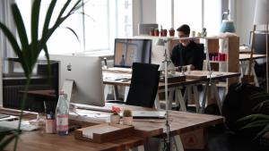 An office with several Mac workstations on desks.