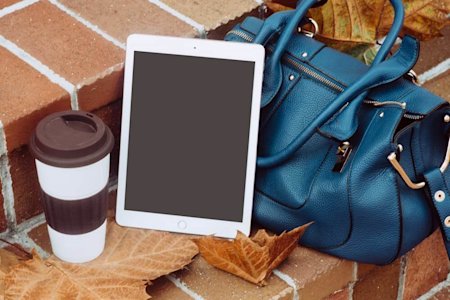An iPad tablet sitting on steps next to a bag and coffee.