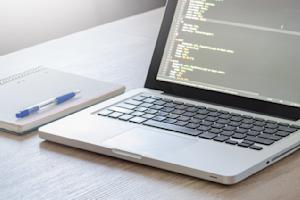 A laptop and notebook on a desk.
