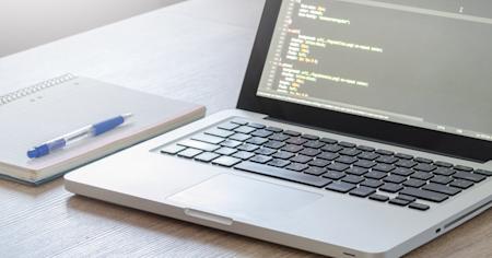 A laptop and notebook on a desk.