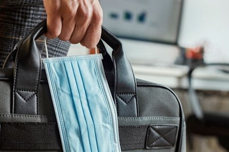 Man holding laptop case and mask