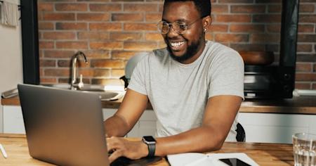 Man with glasses working productively on a laptop in a modern kitchen using Splashtop