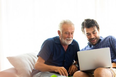 Two men remotely accessing a laptop using Splashtop while sitting on a couch