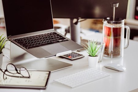 An office desk with a computer, keyboard, and other items.