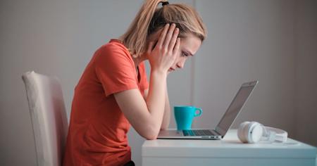 An upset person using their laptop.