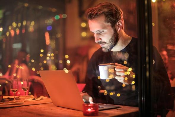 A man in a restaurant using remote desktop software on his laptop to work from anywhere.