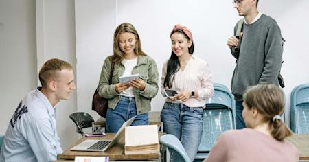 A group of students sitting in a classroom with various digital devices.