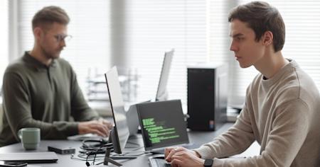 Two IT professionals working on endpoint security with EDR tools in an office.