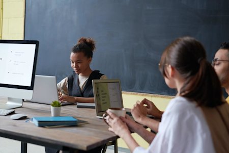 Young woman working on a laptop in a collaborative office space showcasing the ease of Splashtop's remote access