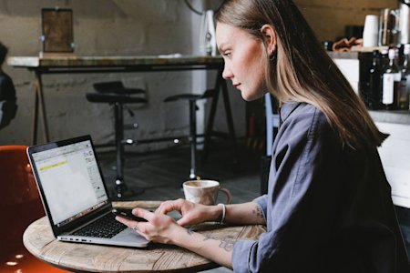 A woman using Splashtop to access her work computer remotely from her laptop at a coffee shop.