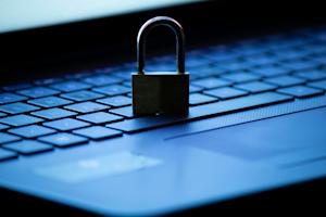 Padlock resting on a laptop keyboard, symbolizing IT data security and protection.