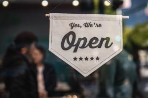 A sign saying "Yes, we're open" hanging in a small business's window.