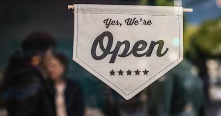 A sign saying "Yes, we're open" hanging in a small business's window.