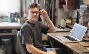 An IT help desk technician smiling in front of his computer at his desk.