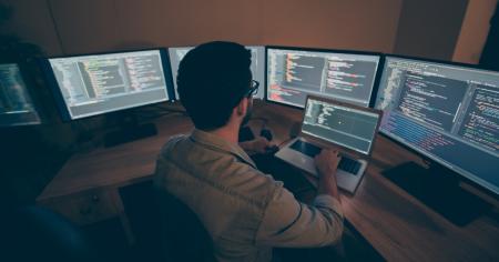 Man using computer with multiple screens