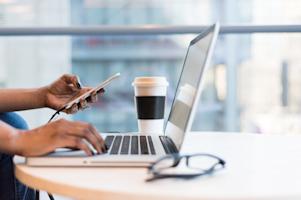 A person using a laptop and smartphone.
