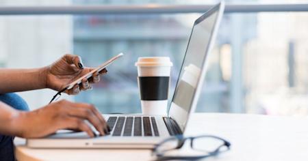 A person using a laptop and smartphone.