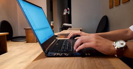 Hands typing on the keyboard of a laptop.